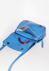 Borsa a tracolla blu in pelle con chiusura a pattina. L'interno presenta una fodera grigio chiaro, tasca con zip e un nastro rosso per tirare. Due bottoni neri sulla pattina.