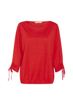 Raudona, laisvai krentanti tunika su apvali iškirpte, trimis ketvirtadaliais rankovėmis ir virvutėmis ant rankogalių. Minkšta tekstūra, kasdieniškas dizainas.