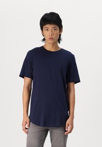 Marineblaues T-Shirt mit Rundhalsausschnitt, kurzen Ärmeln, aus Baumwolle gefertigt, mit einem dezenten Logo auf der linken Brust und einem abgerundeten Saumdesign.
