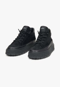 Czarne zamszowe sneakersy z grubą platformą, z gładkim czarnym skórzanym akcentem i okrągłymi sznurowadłami. Logo na języku.