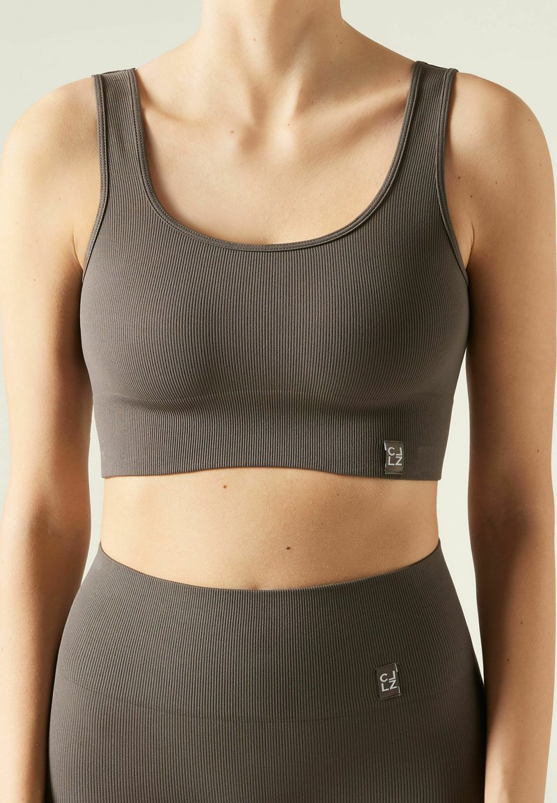 Grå ribbad sportbh med vida axelremmar, rundad halsringning och cropped design, med en liten logotag på framsidan.