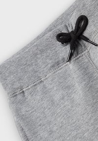 Gray sweatpants with a textured fabric and ribbed waistband, featuring a black drawstring and silver aglet accents.
