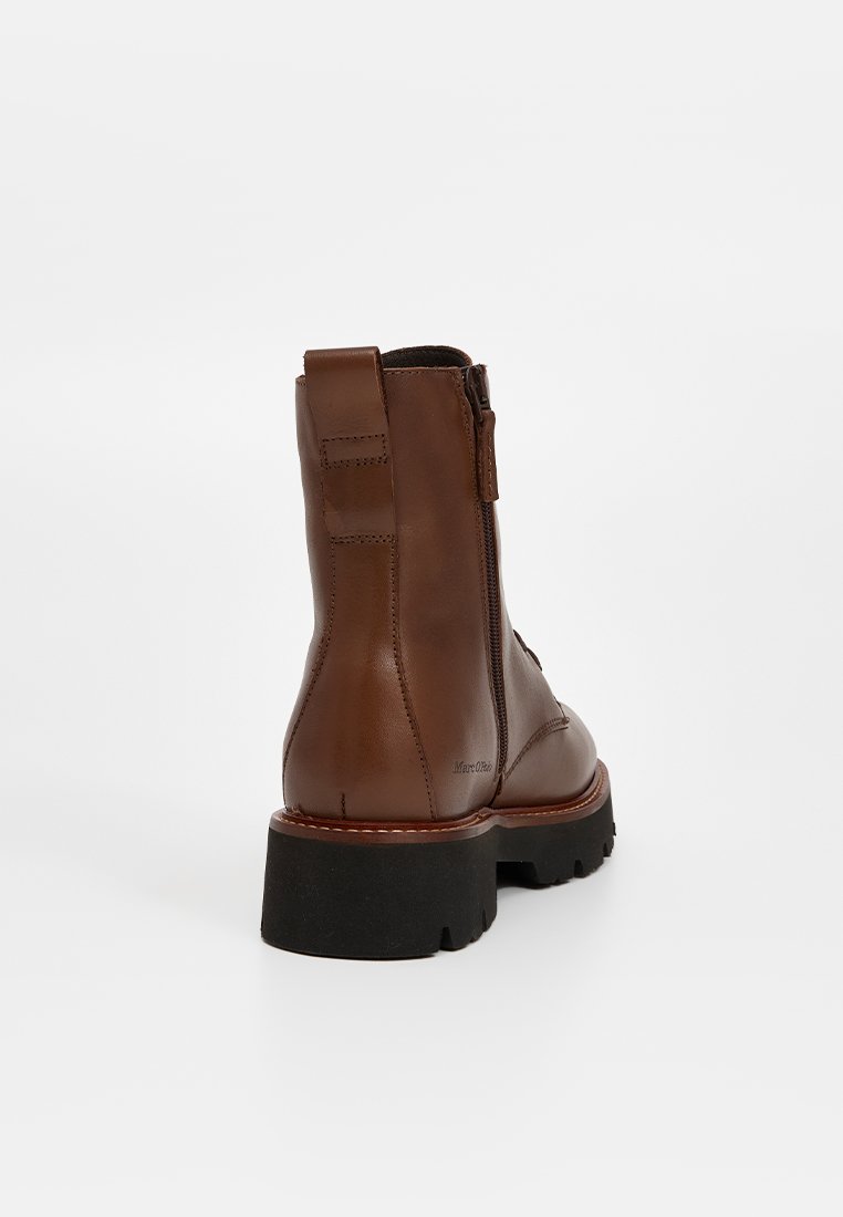 Braune Lederstiefeletten mit einem Reißverschluss hinten, verstärktem Absatz und schwarzer Gummisohle. Klare Linien und minimalistisches Design.