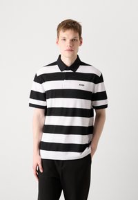 Svart og hvit stripete polo skjorte laget av bomull, med krage, tre knapper og en liten 'BOSS' logo på brystet.