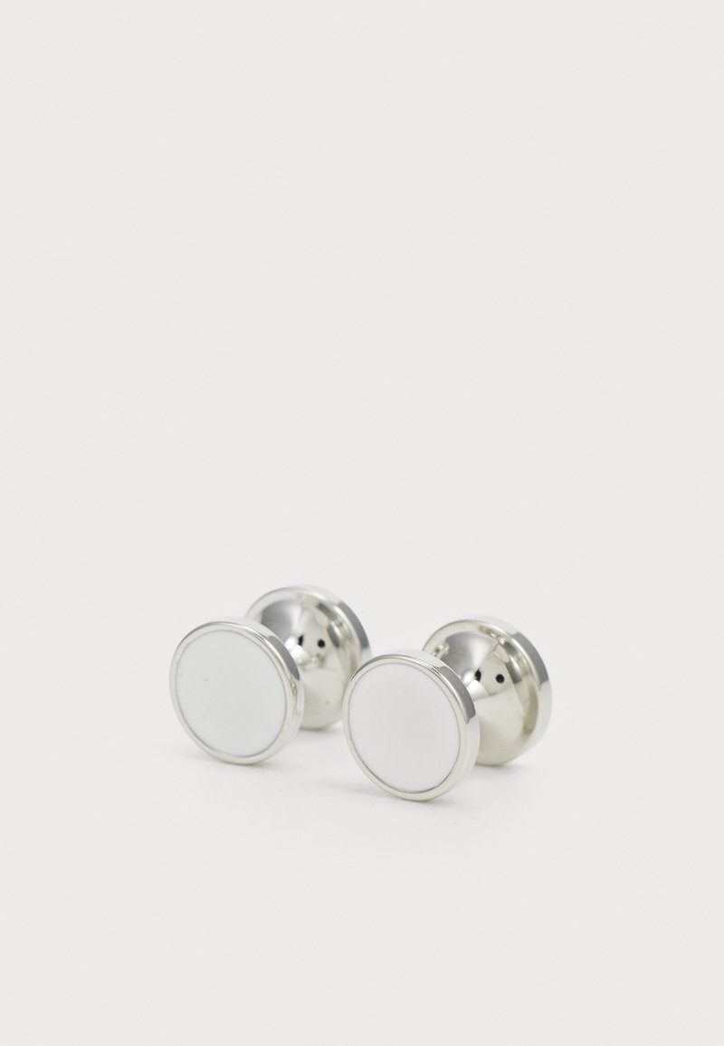 Silverfärgade manschettknappar med en polerad yta, med rund form och en vit mitt. Slät textur med en ren design.
