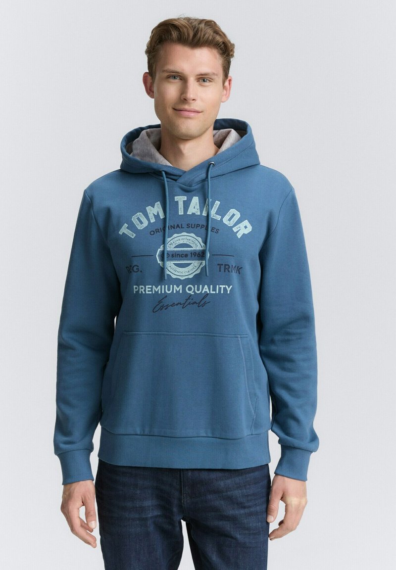 Blauer Hoodie mit grauem Innenfutter, ausgestattet mit einer Fronttasche und grafischem Text. Hergestellt aus einem glatten Material, mit gerippten Bündchen und Saum.