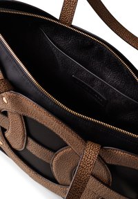 Sac fourre-tout en cuir noir avec des accents texturés marron, fermeture zippée et poche intérieure. Doté de doubles poignées et d'un intérieur lisse et spacieux.
