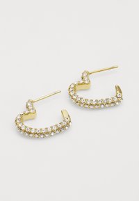 Gouden creolen met een golvend ontwerp, versierd met heldere rhinestones aan de buitenkant en een rechte pin voor bevestiging.