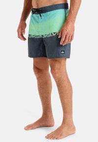 Męskie szorty pływackie w gradientzie od jasnej zieleni do ciemnoszarego, wykonane z lekkiego materiału, z akcentem logo i elastycznym paskiem na sznurku.