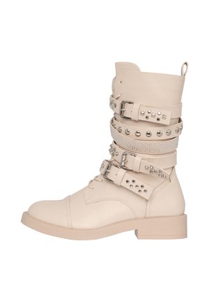 Stivale alla caviglia in pelle beige con più cinturini decorativi che presentano borchie in argento e strass, punta rotonda e tacco basso a blocco.