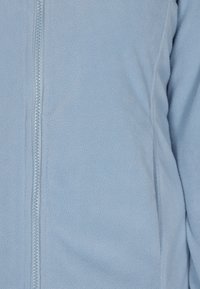 Giacca in pile blu chiaro con una texture liscia, dotata di una zip a lunghezza intera e dettagli di cucitura sottile lungo le cuciture.