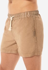 Costumi da bagno khaki realizzati in tessuto leggero, con un elastico in vita e cordino, e tasche laterali. Texture liscia con un design informale.
