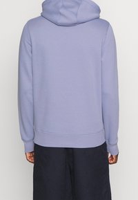 Felpa con cappuccio in lavanda, realizzata in un tessuto morbido, con polsini e orlo a coste, dal taglio rilassato e design minimalista.