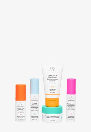 Cinq produits de soin Drunk Elephant avec des bouchons colorés, comprenant des sérums, un nettoyant et une crème, disposés sur un fond blanc.