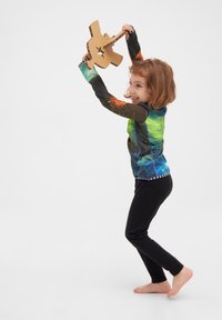 Langærmet skjorte med et farverigt galakseprint, sorte leggings og en papguitar. Skjorten har et farverigt design med stjerne-lignende mønstre.