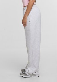 Lysegrå sweatpants lavet af blødt materiale, med en afslappet pasform, elastisk talje og sidelommer. Båret med grå sportsko.