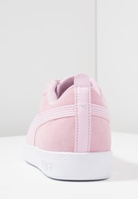 Rosa mockaskor med en vit gummisula, med en slät bakre tab och tonala ränder längs sidorna. Silverfärgad logotyp på häl.