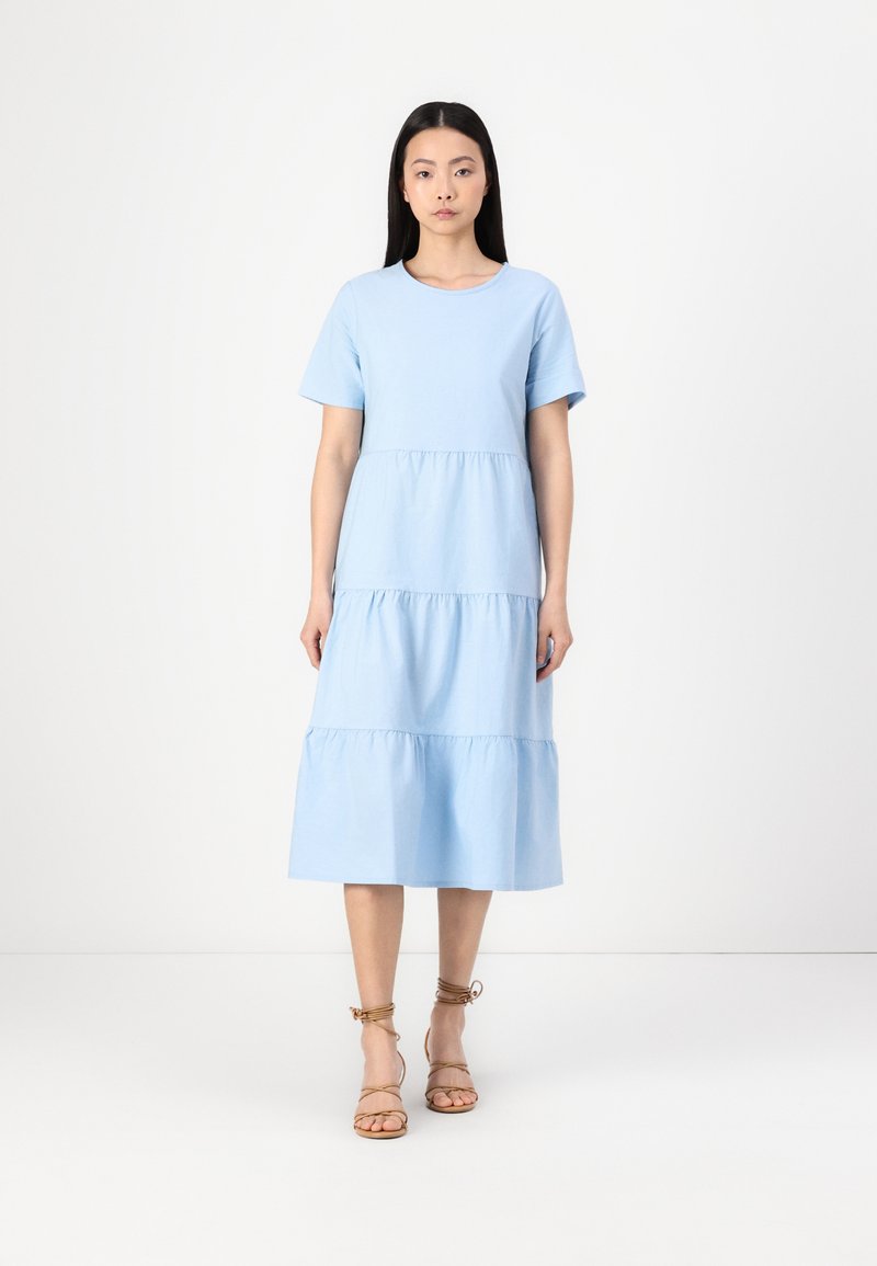 Vestido em azul claro, de algodão, com mangas curtas em camadas, gola redonda, três camadas de tecido e uma bainha inferior fluida.