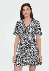 Robe à manches courtes avec un imprimé zèbre noir et blanc, décolleté en V et ourlet ondulé, fabriquée en tissu léger.