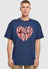 Marineblå bomulds T-shirt med korte ærmer, prydet med et stort hjerteformet grafik i lyserød, der står "SPREAD LOVE" med fede bogstaver.