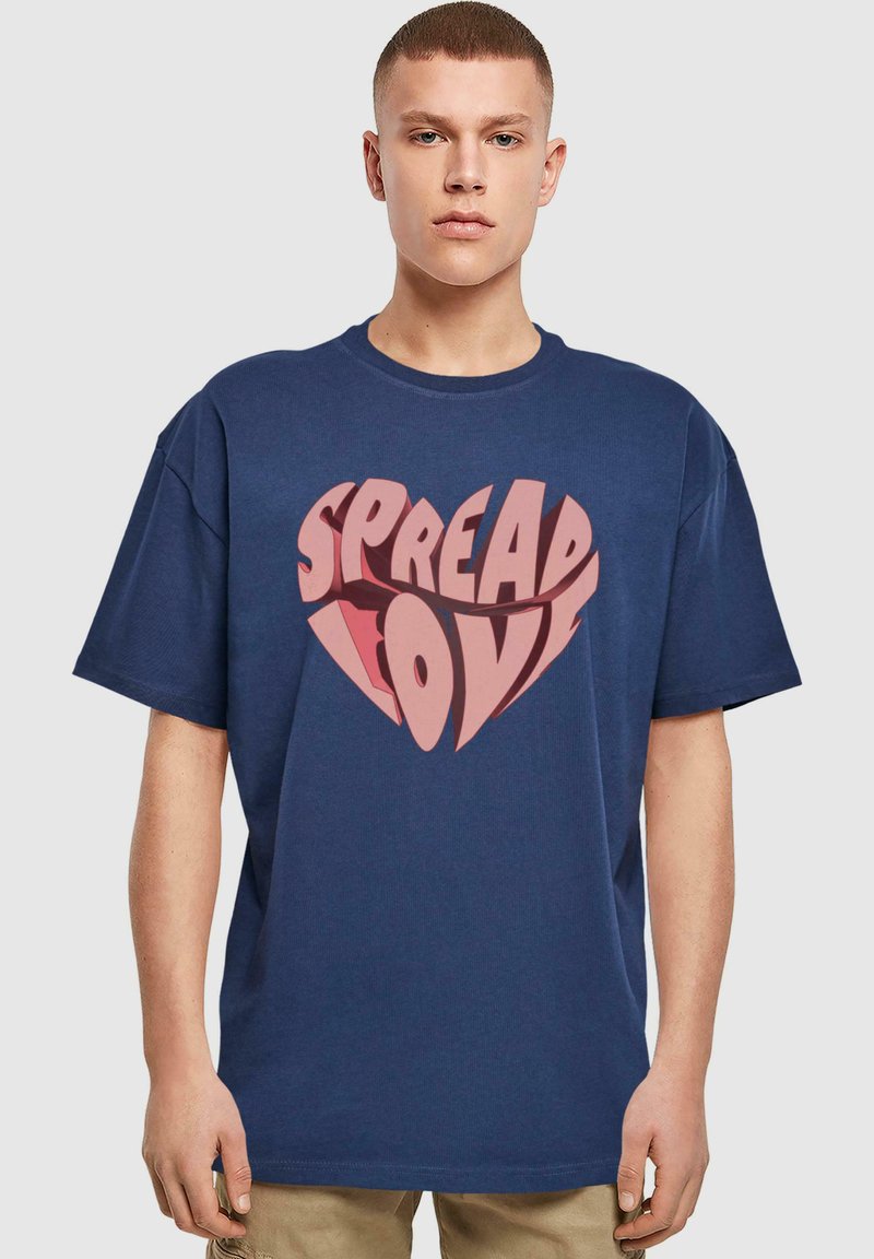 Marineblauw katoenen t-shirt met korte mouwen, voorzien van een grote hartvormige grafiek in lichtroze met de tekst "SPREAD LOVE" in vetgedrukte letters.