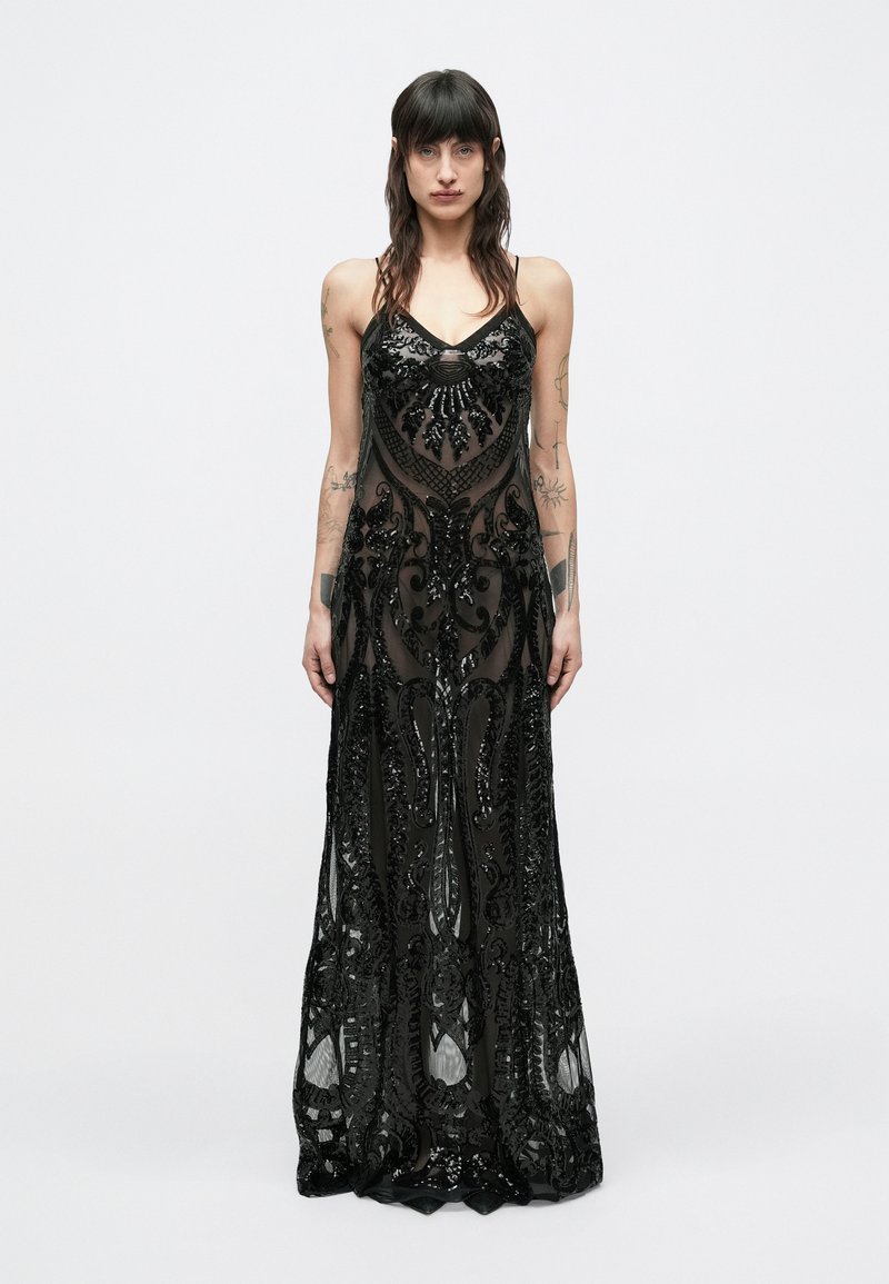 Mustast läbipaistvast kangast põrandani ulatuv kleit, millel on keerukad helmestega mustrid. Omadusteks on õhukesed rihmad ja detailirohked litrite kaunistused.