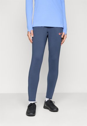 Marineblå leggings lavet af strækstof, med en tætsiddende pasform og et lille orange Nike-logo på venstre lår.