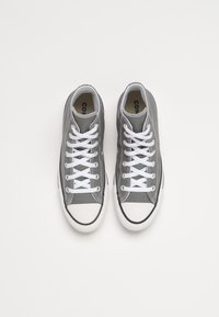 Grijze canvas hoge sneakers met witte veters, rubberen neuskap en zwarte middenzooldetails. Interieur heeft een beige voering.
