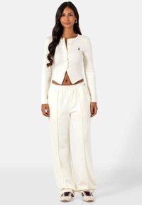 Witte, geribbelde cropped cardigan met lange mouwen, knoopsluiting en geborduurd logo, gecombineerd met witte high-waisted wijde broek.