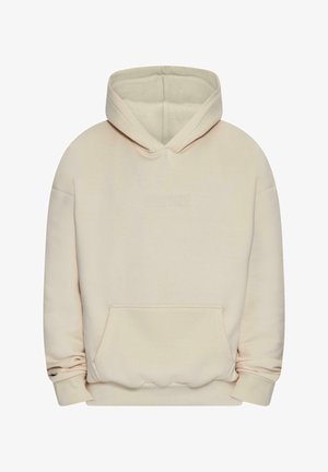 Beige kapuutsiga streimpusa, mis on valmistatud pehmest kangast, ees on suur tasku, pikal varrukal ja reguleeritav kapuuts. Ees on diskreetne reljeefne logo.