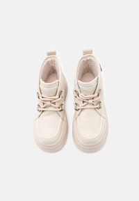 Beige ankelstøvler med en glat overdel, blødt for, teksturerede snørebånd og metalliske hardware-accenter. Har en rund tå og polstret krave.