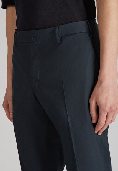 Pantalones azul marino de tejido ligero, con una textura suave, bolsillos laterales y una cintura de altura media con un sutil brillo.
