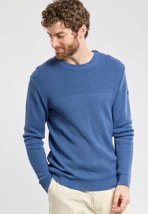 Pull en tricot bleu avec un design texturé horizontal sur la poitrine. Présente un col rond et des poignets et ourlet côtelés.