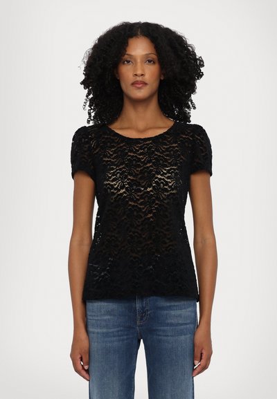 Black lace short-sleeve top featuring a floral pattern and a rounded neckline, paired with blue jeans. Textured, semi-transparent material.