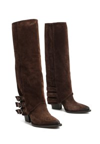 Brązowe zamszowe kozaki sięgające do kolan z ostrym noskiem, z trzema zapięciami na zewnątrz i pionowymi wycięciami na pięcie.
