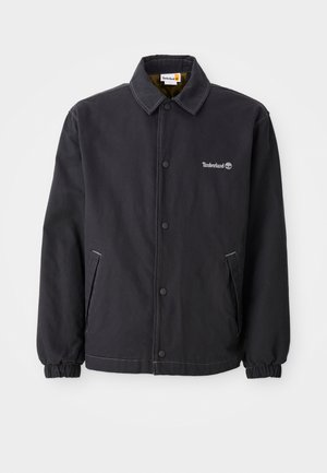 Black Timberland jacket featuring a button-up front, elastic cuffs, two side pockets, and a lightweight, textured fabric.