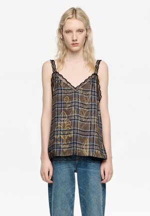 Brązowy top bez rękawów w kratę w niebiesko-żółtych odcieniach, z koronkowym wykończeniem dekoltu i dołu. Noszony z niebieskimi dżinsami.