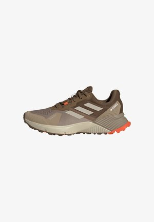 Brown athletic shoes featuring a mesh upper, three white stripes, orange accents, and a textured rubber sole. Designed for outdoor activities.