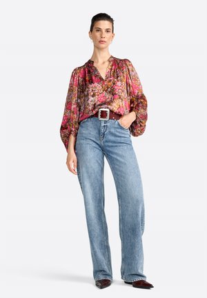Flowy floral blouse in pink and brown tones, with a v-neck and long puff sleeves, paired with high-waisted light blue jeans and a brown belt.