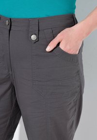 Šedé cargo kalhoty vyrobené z měkké tkaniny, s knoflíkovým zapínáním, bočními kapsami a hladkou texturou. Pás je mírně tvarovaný.