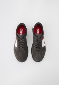 Sneaker in suede grigio con accenti rossi e crema, caratterizzati da una punta rotonda, design con lacci e logo in contrasto sulla soletta.