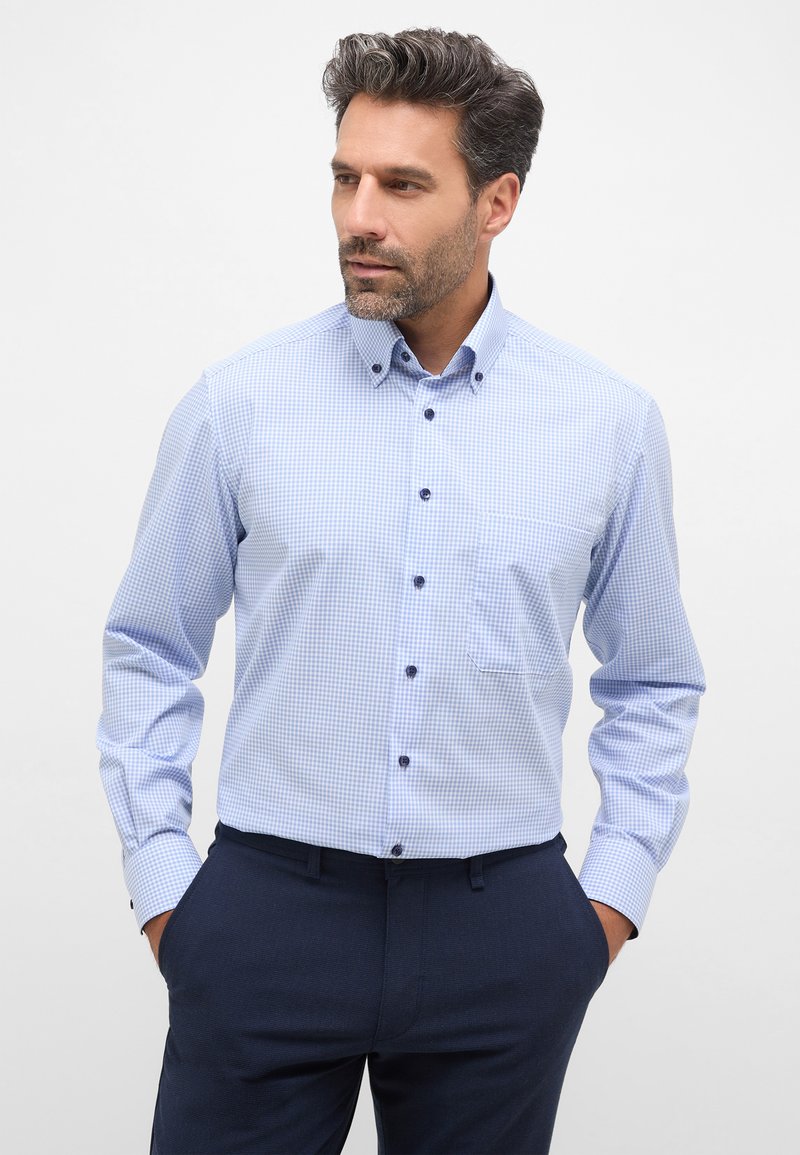 Camicia a quadretti azzurri con colletto button-down, maniche lunghe e bottoni blu. Presenta una tasca sul lato sinistro.