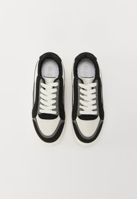 Baskets noir et blanc en mesh et daim, à bout rond, avec des lacets blancs et des cols rembourrés. Semelles en caoutchouc avec des détails texturés.