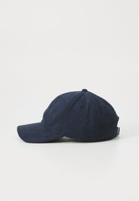 Marineblå corduroy baseball cap med buet skygge, justerbar rem bagpå og broderet logo foran. Den strukturerede stoftilførsel tilføjer detalje.