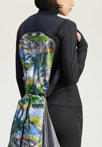 Mochila con un estampado de naturaleza que presenta árboles, rocas y un cielo azul; fabricada con un tejido duradero, con correas ajustables y un diseño elegante.