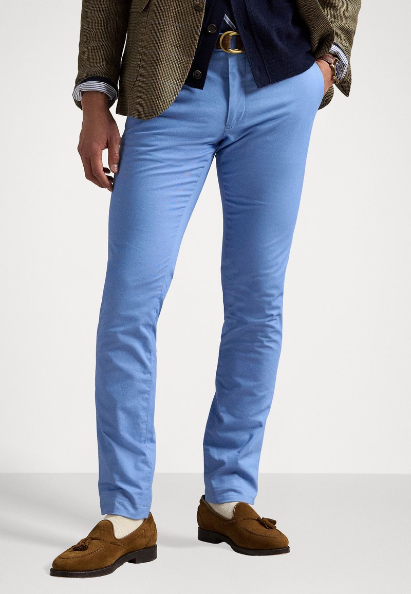 Ανοιχτό μπλε chinos φτιαγμένο από μαλακό βαμβάκι, με στενή εφαρμογή, επίπεδο μπροστινό μέρος και πλαϊνές τσέπες, συνδυασμένο με καφέ σουέτ λοφάς.