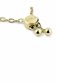 Collana a catena color oro con pendente rotondo caratterizzato dall'incisione "FURLA", adornato da due accenti sferici pendenti. Finitura luminosa e brillante.