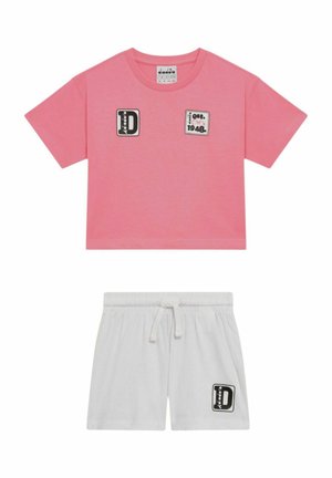T-shirt corta a maniche corte rosa con toppe nere e bianche e pantaloncini bianchi con coulisse e toppa abbinata sulla gamba sinistra.