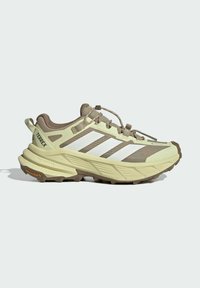 Beige and brown Adidas Terrex trail shoe with white stripes, lace lock system, and rugged Continental rubber sole.