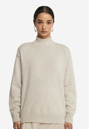Krämsfärgad polotröja gjord av ett mjukt material, med en ribbad halsringning och fåll, i en avslappnad passform med långa ärmar.